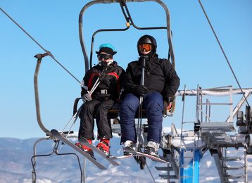 People using chairlift at mountain ski resort. Winter vacation