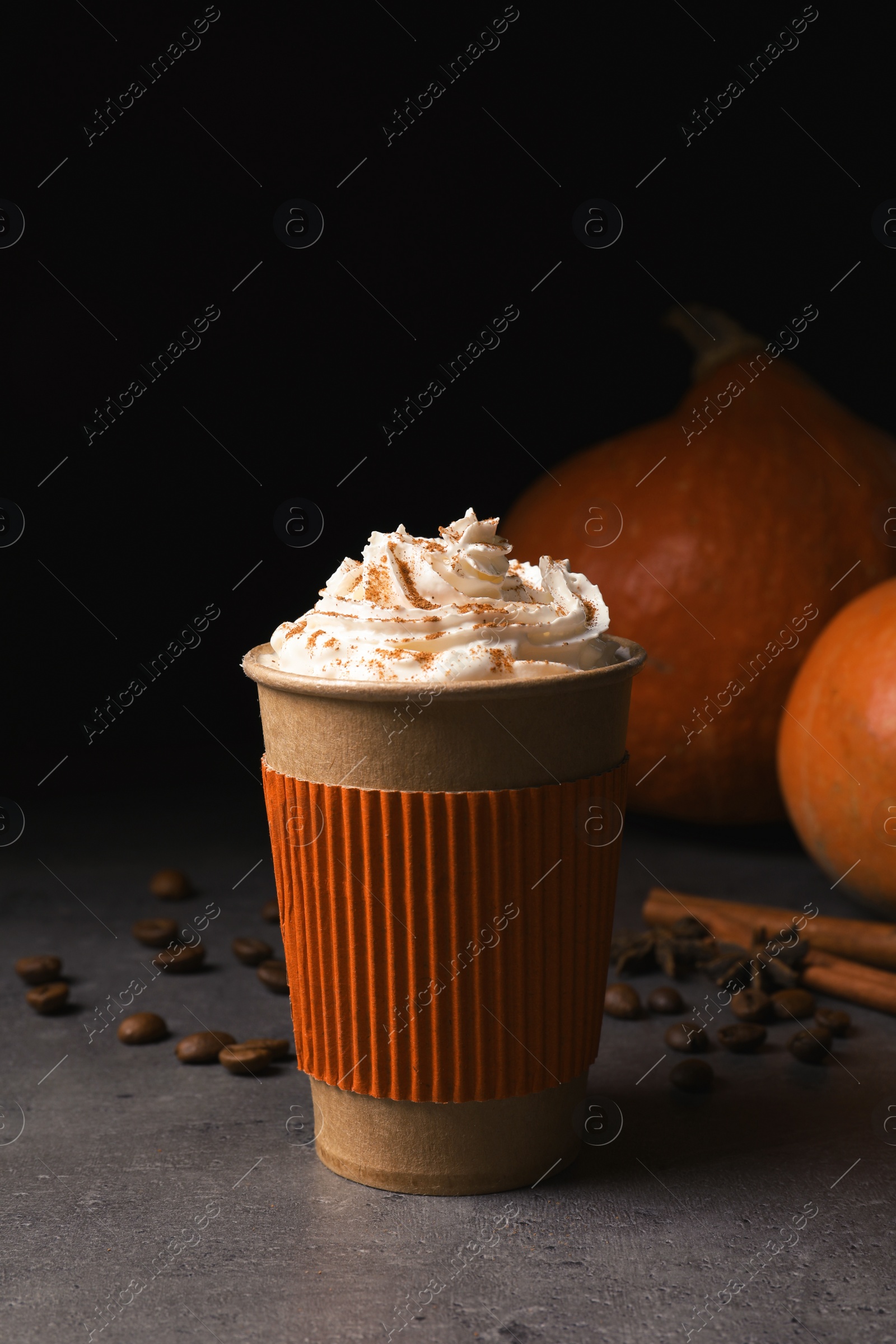 Photo of Paper cup with tasty pumpkin spice latte on gray table