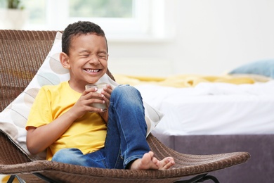 Adorable African-American boy with glass of milk at home