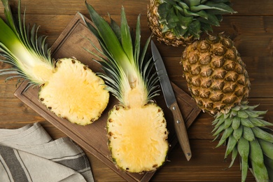 Photo of Whole and cut pineapples on wooden table, flat lay