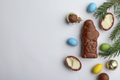 Photo of Flat lay composition with chocolate Santa Claus, fir tree twigs and sweets on white background, space for text