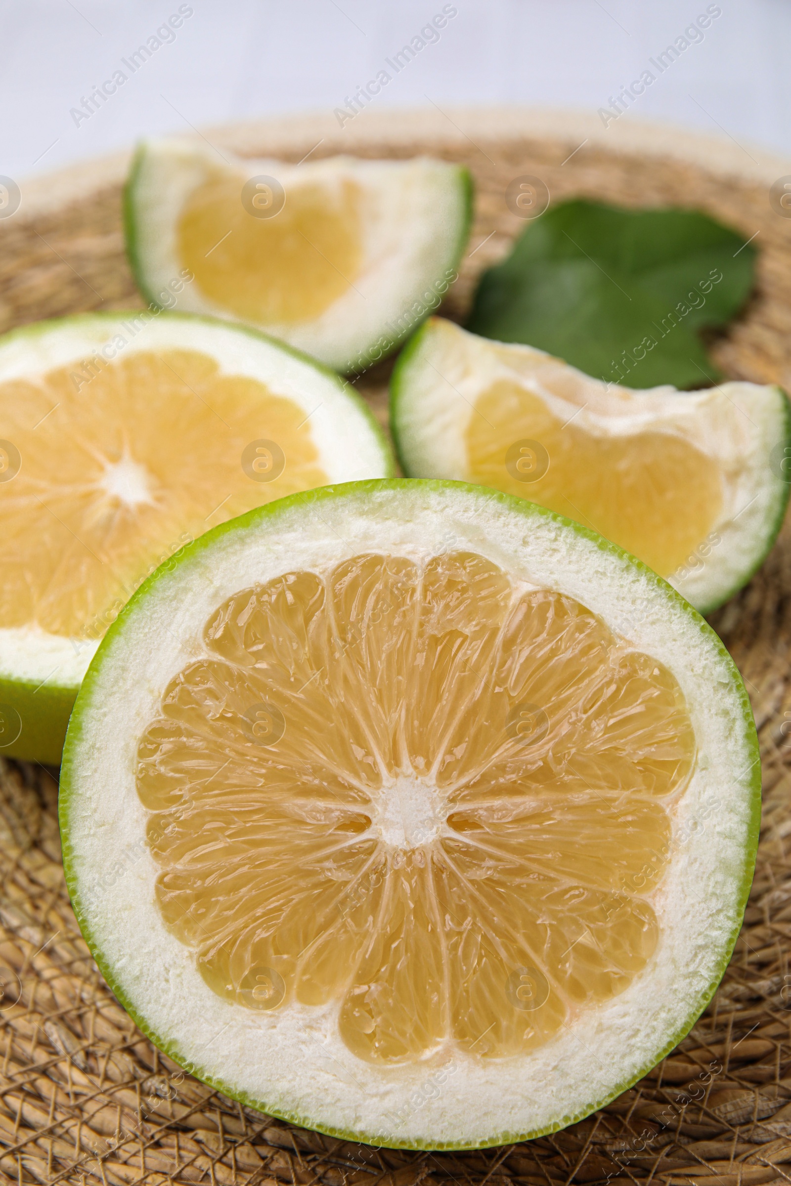 Photo of Cut sweetie fruits on wicker mat, closeup