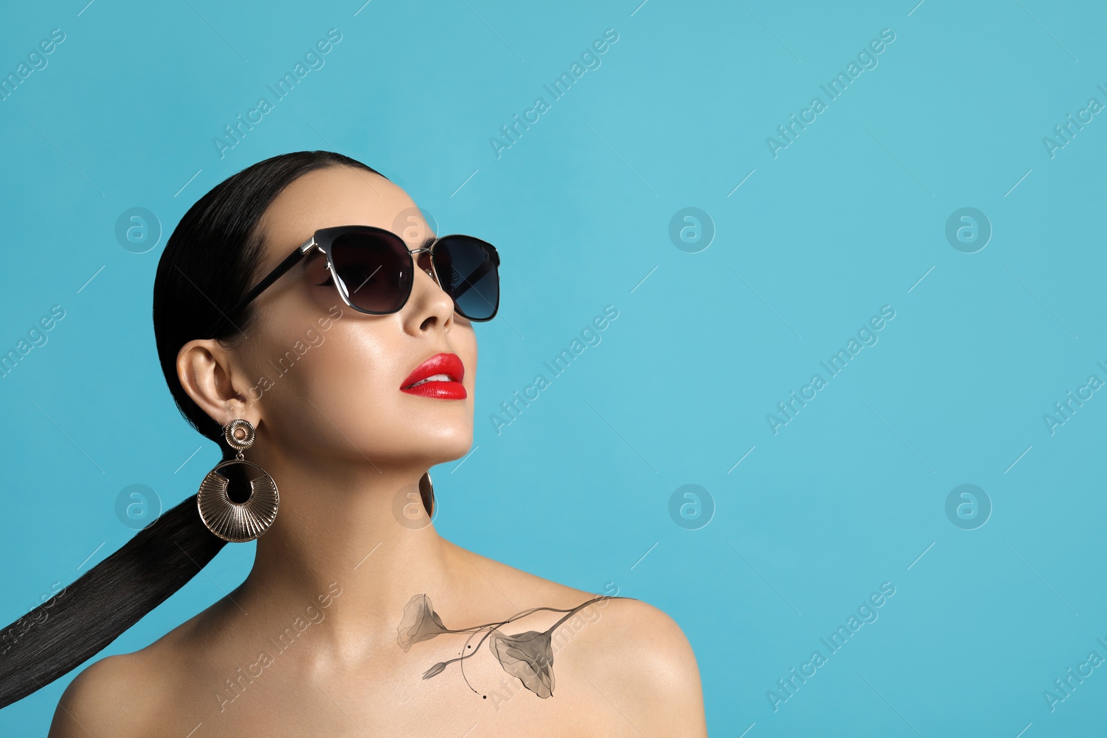 Image of Stylish young woman with beautiful flower tattoo on turquoise background, space for text