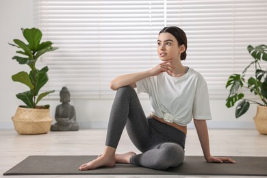 Beautiful girl sitting on yoga mat in studio