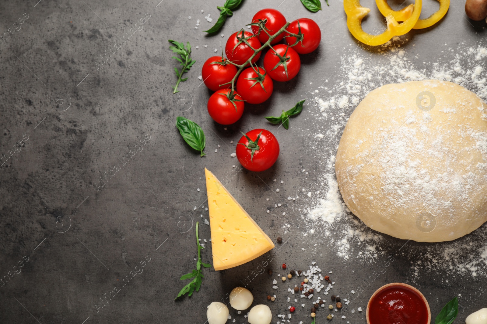 Photo of Flat lay composition with dough and fresh pizza ingredients on grey table, space for text