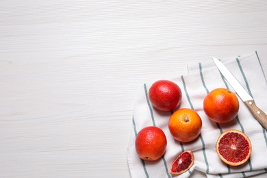 Photo of Fresh ripe red oranges on white wooden table, flat lay. Space for text
