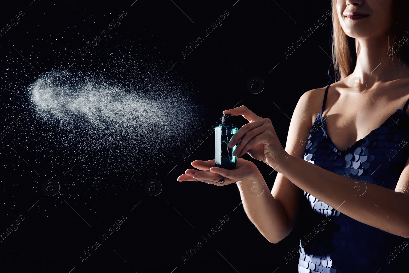 Photo of Young woman spraying perfume on black background, closeup