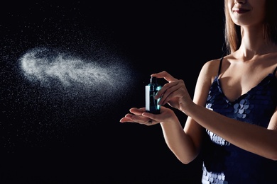 Photo of Young woman spraying perfume on black background, closeup