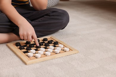 Photo of Playing checkers. Boy thinking about next move on floor in room, closeup