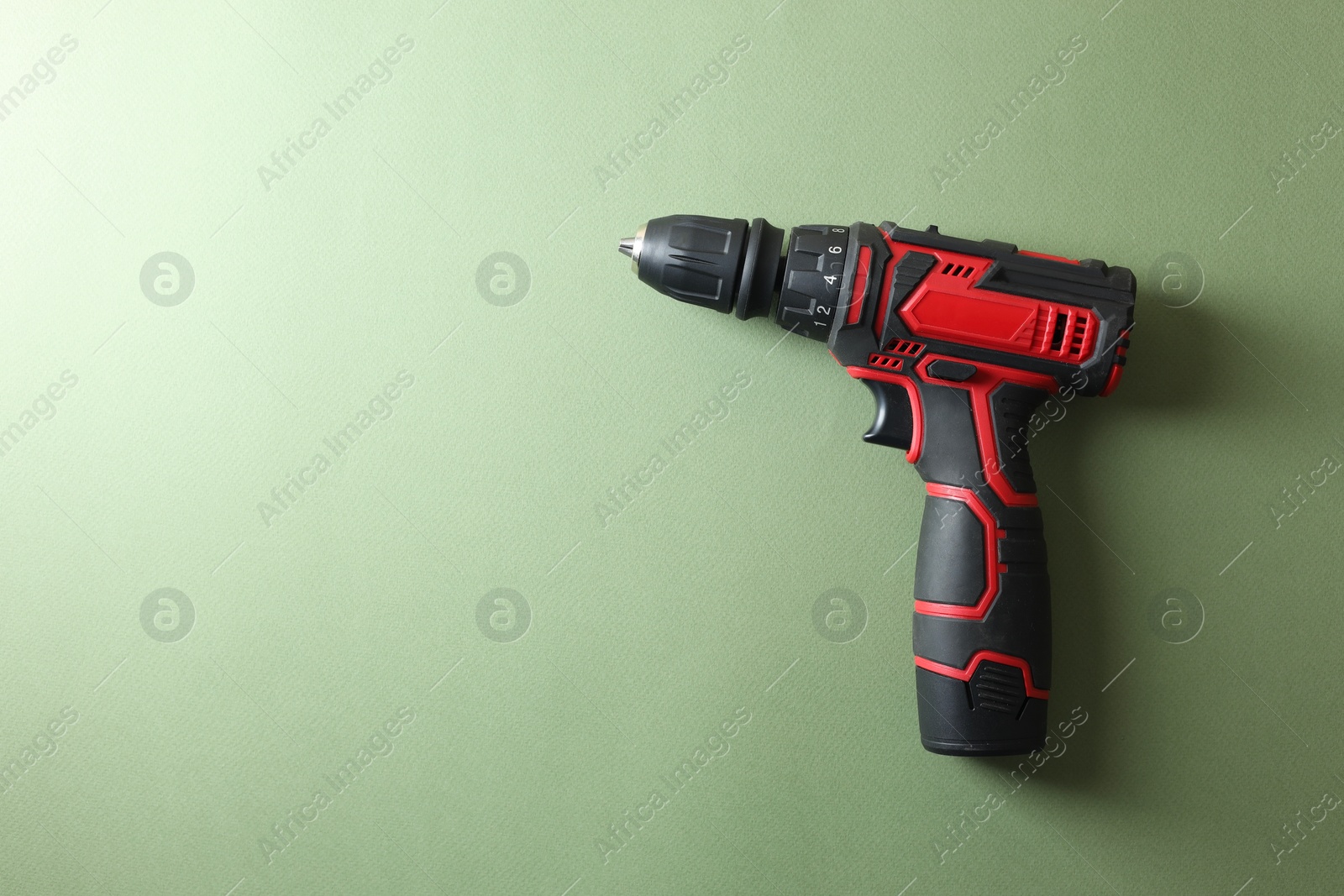 Photo of Electric screwdriver on pale green background, top view. Space for text