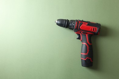 Electric screwdriver on pale green background, top view. Space for text