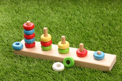 Photo of Stacking and counting game wooden pieces on artificial grass. Educational toy for motor skills development