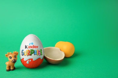 Photo of Slynchev Bryag, Bulgaria - May 25, 2023: Kinder Surprise Eggs, capsule and toy deer on green background, space for text