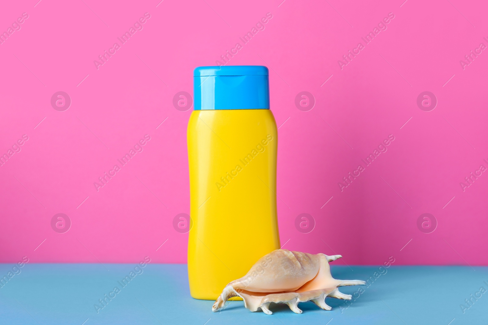 Photo of Suntan product and seashell on color background