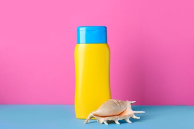 Suntan product and seashell on color background