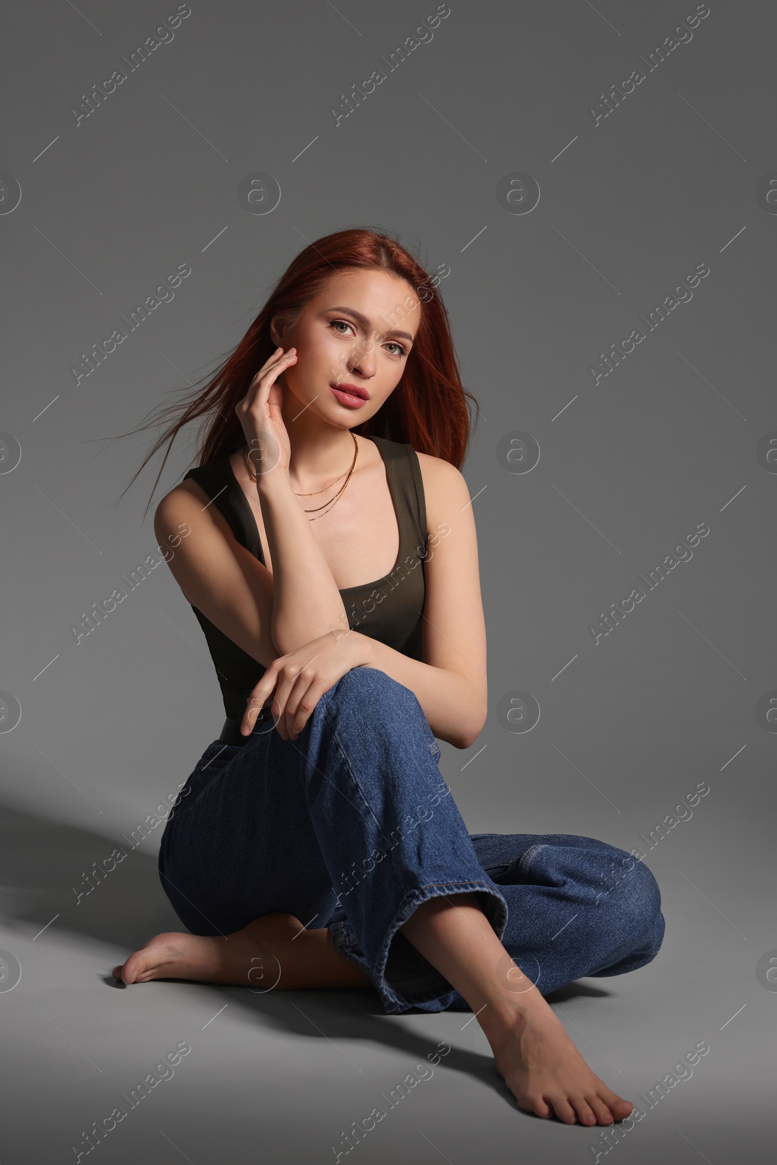 Photo of Beautiful young woman sitting on gray background