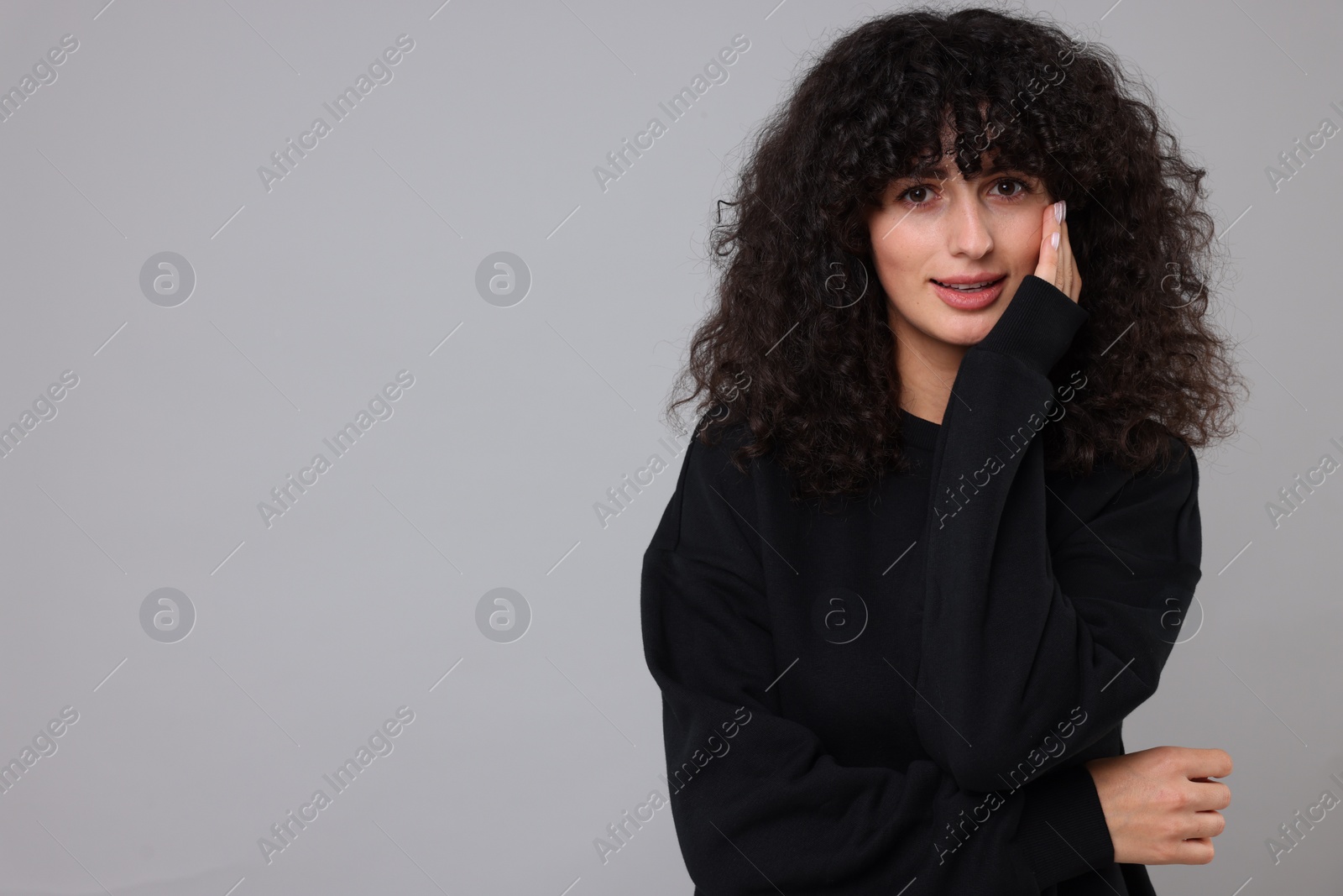 Photo of Young woman in stylish black sweater on light grey background, space for text