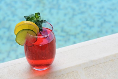 Photo of Glass of delicious cocktail near swimming pool, space for text. Refreshing drink