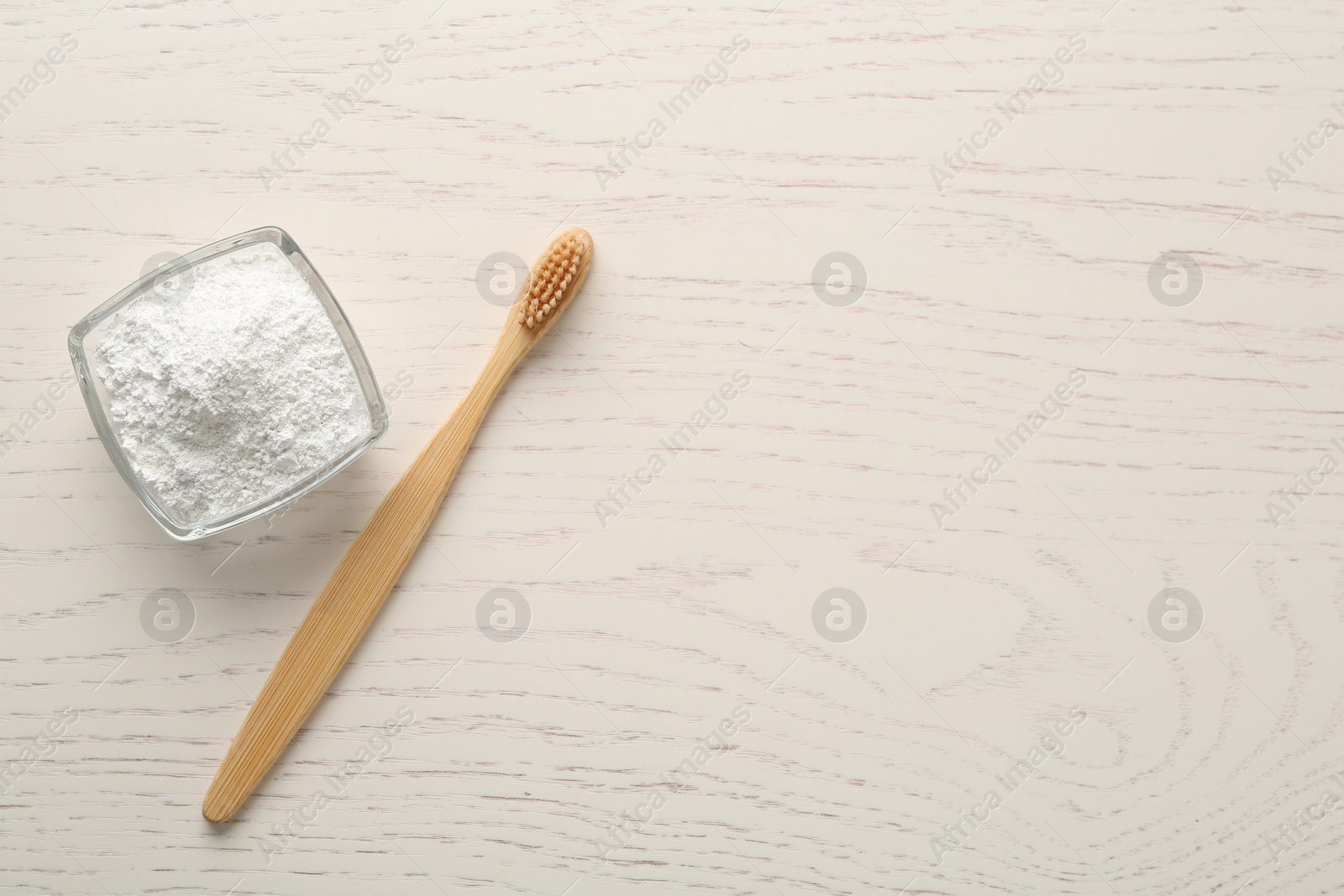 Photo of Tooth powder and brush on white wooden table, flat lay. Space for text