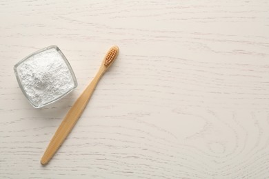 Photo of Tooth powder and brush on white wooden table, flat lay. Space for text