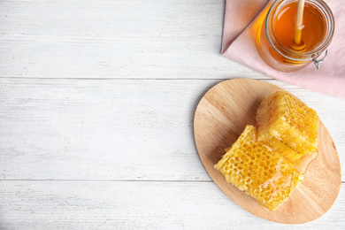 Flat lay composition with delicious honey on white wooden table. Space for text