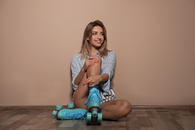 Young woman with retro roller skates against color wall