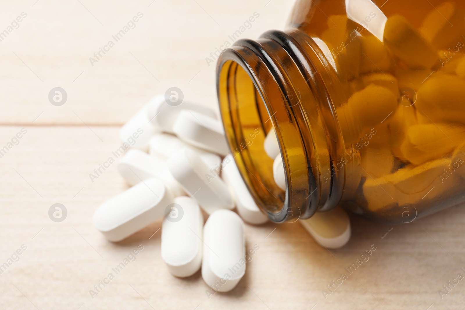 Photo of Bottle and vitamin pills on wooden table, closeup