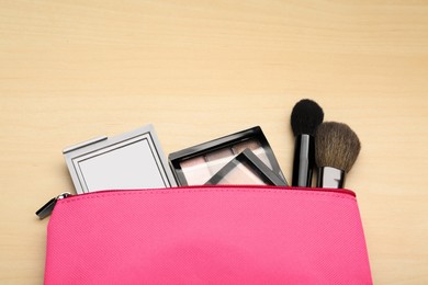 Photo of Cosmetic bag with pocket mirror and makeup products on wooden background, flat lay