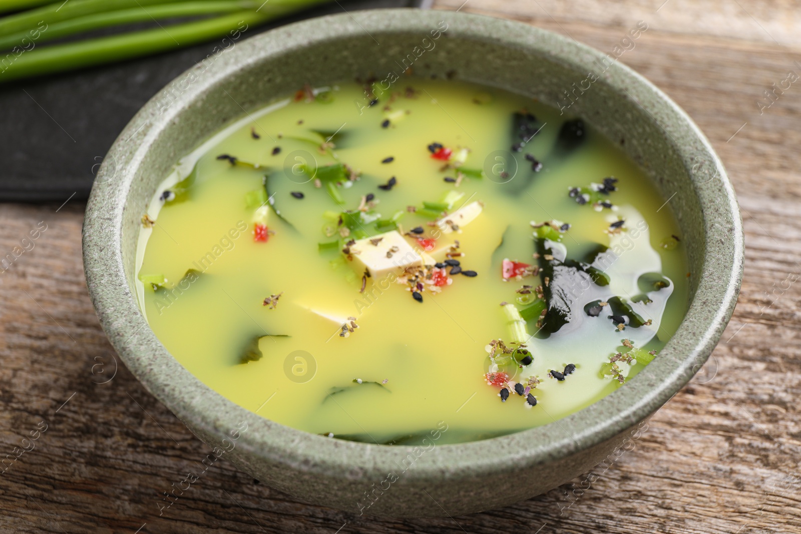 Photo of Bowl of delicious miso soup with tofu on wooden table, closeup