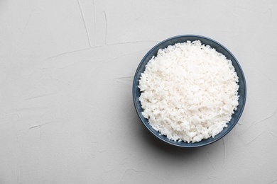 Photo of Bowl of boiled rice on color background, top view with space for text