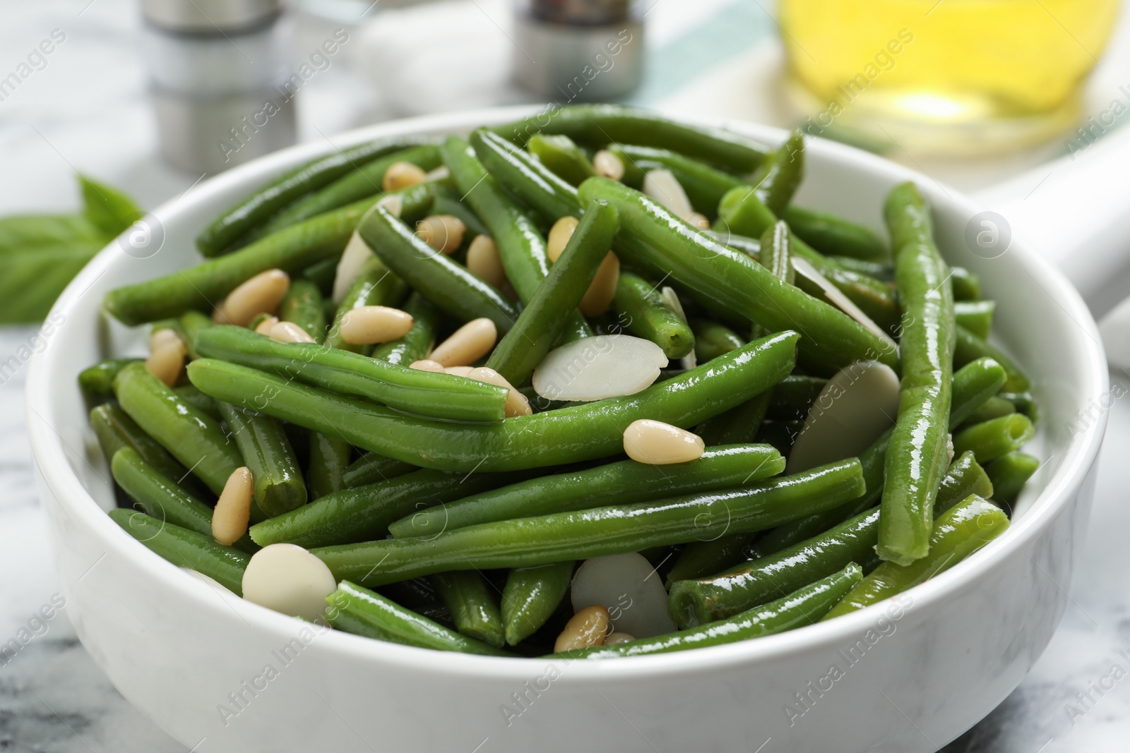 Photo of Bowl of tasty salad with green beans on white marble table, closeup