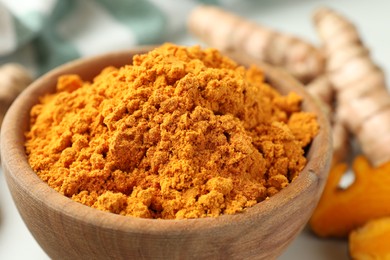 Photo of Aromatic turmeric powder in bowl on table, closeup