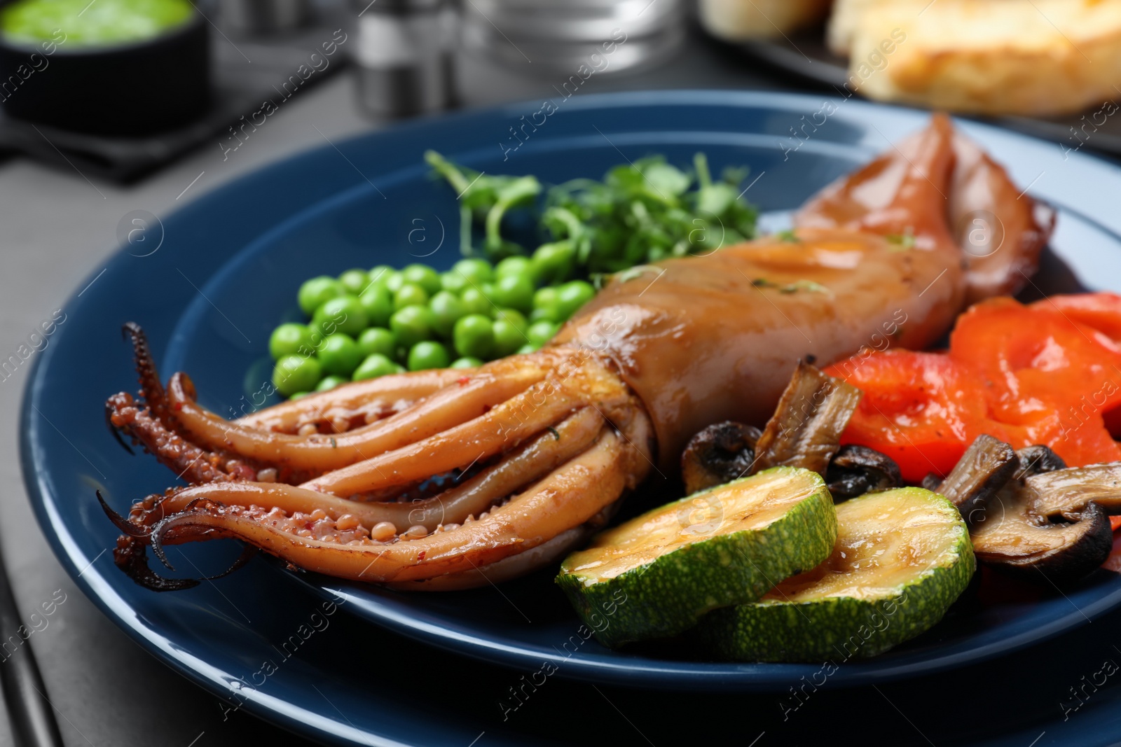 Photo of Delicious grilled squid served on black table, closeup