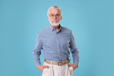 Portrait of stylish grandpa with glasses on light blue background