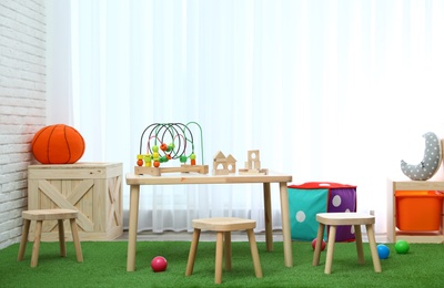 Stylish playroom interior with toys and modern wooden furniture