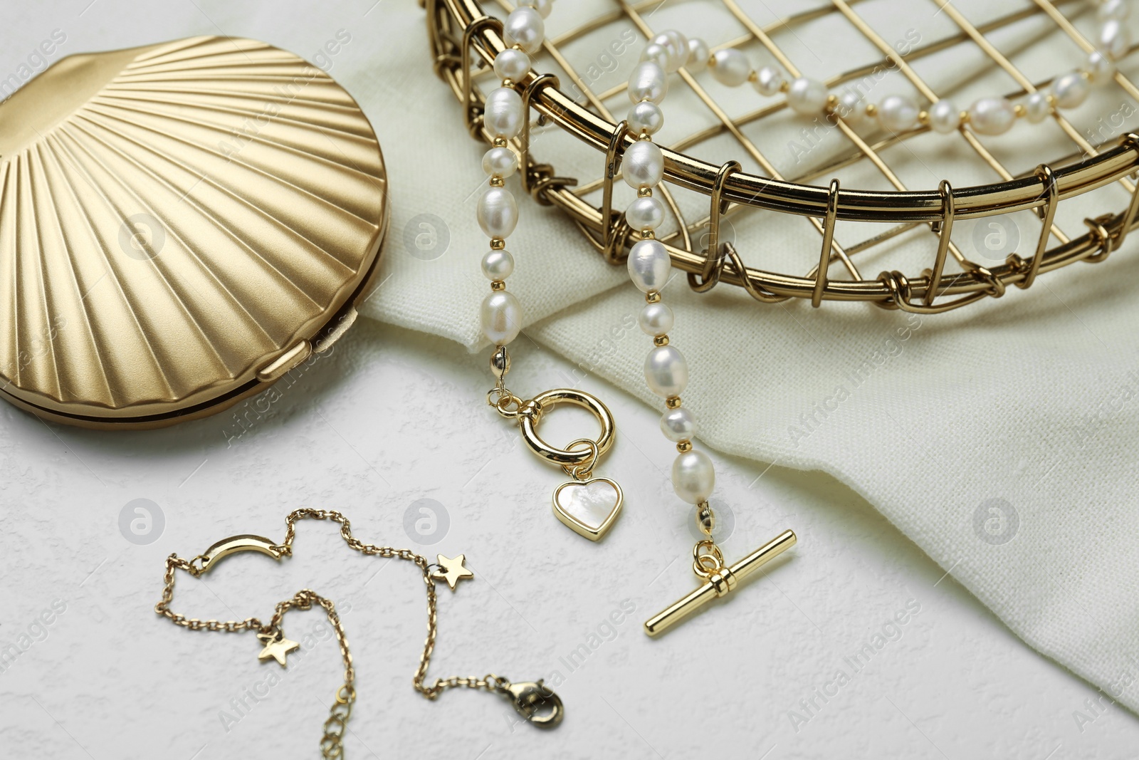 Photo of Different elegant jewelry and cosmetic pocket mirror on white table, closeup