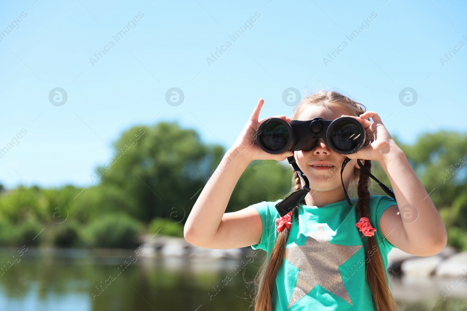 Photo of Little girl with binoculars outdoors. Summer camp