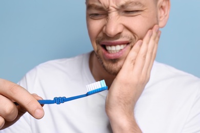 Young man suffering from toothache on grey background