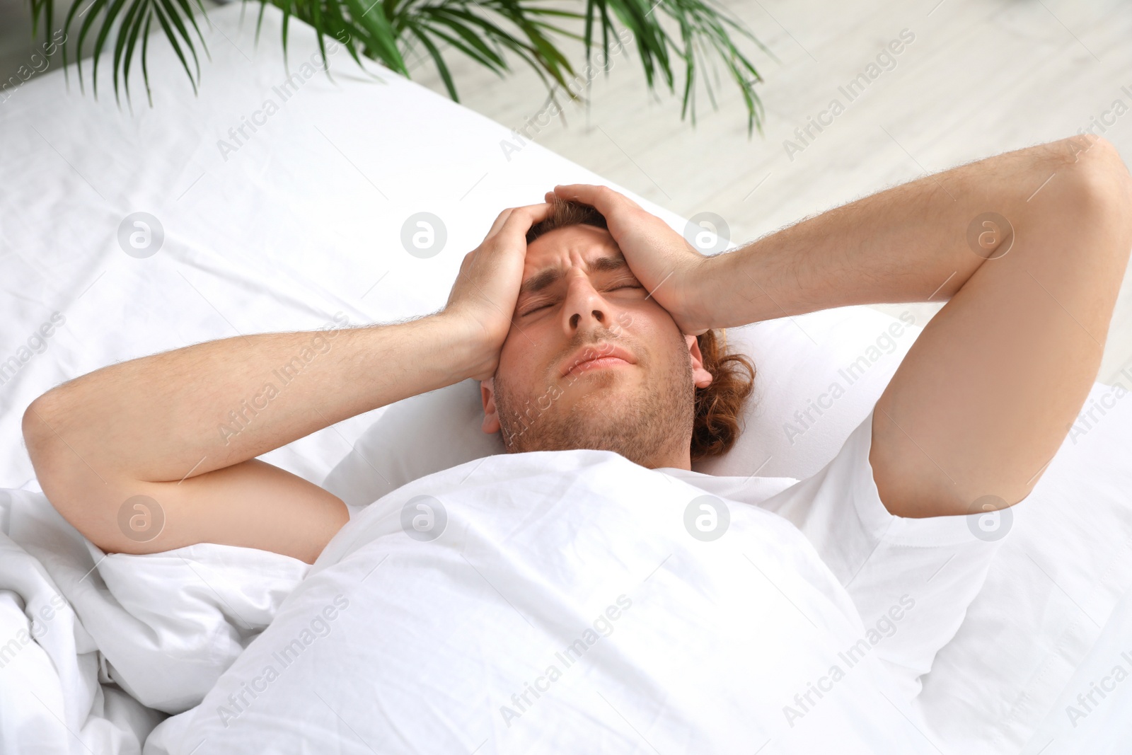 Photo of Handsome young man lying under blanket in morning. Bedtime