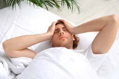 Photo of Handsome young man lying under blanket in morning. Bedtime