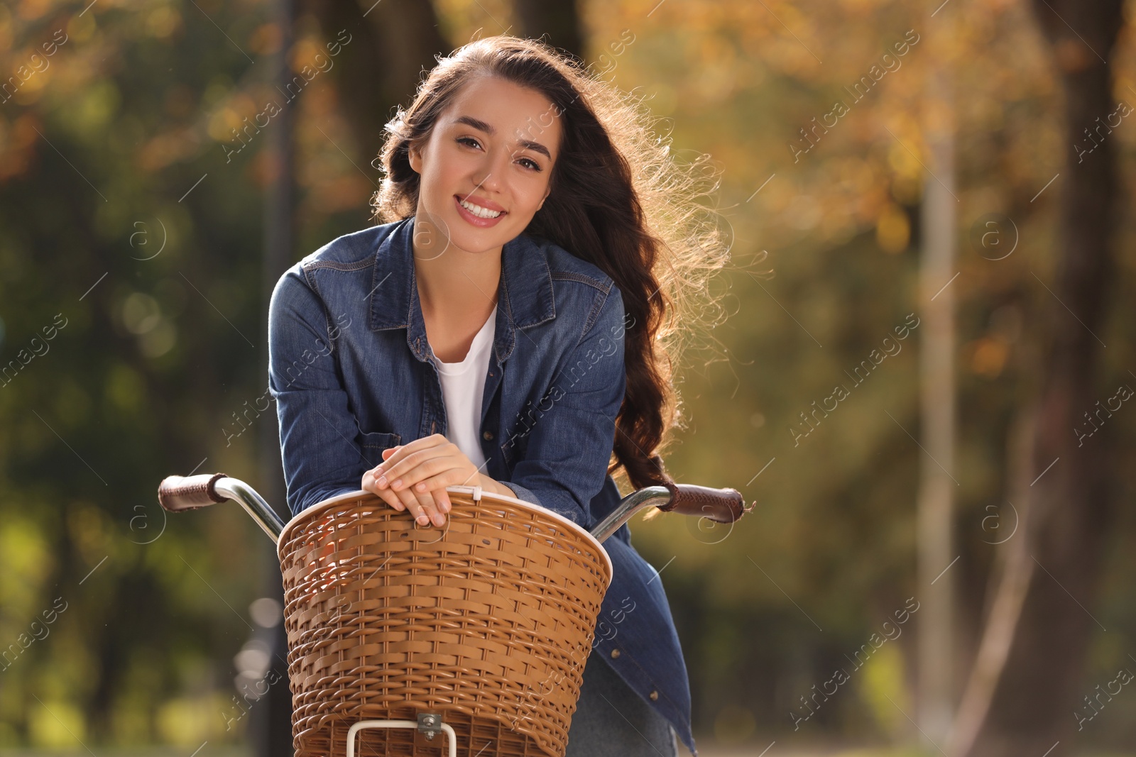 Photo of Young woman with bicycle in autumn park, space for text