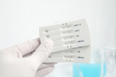 Photo of Doctor holding two disposable express tests for hepatitis indoors, closeup
