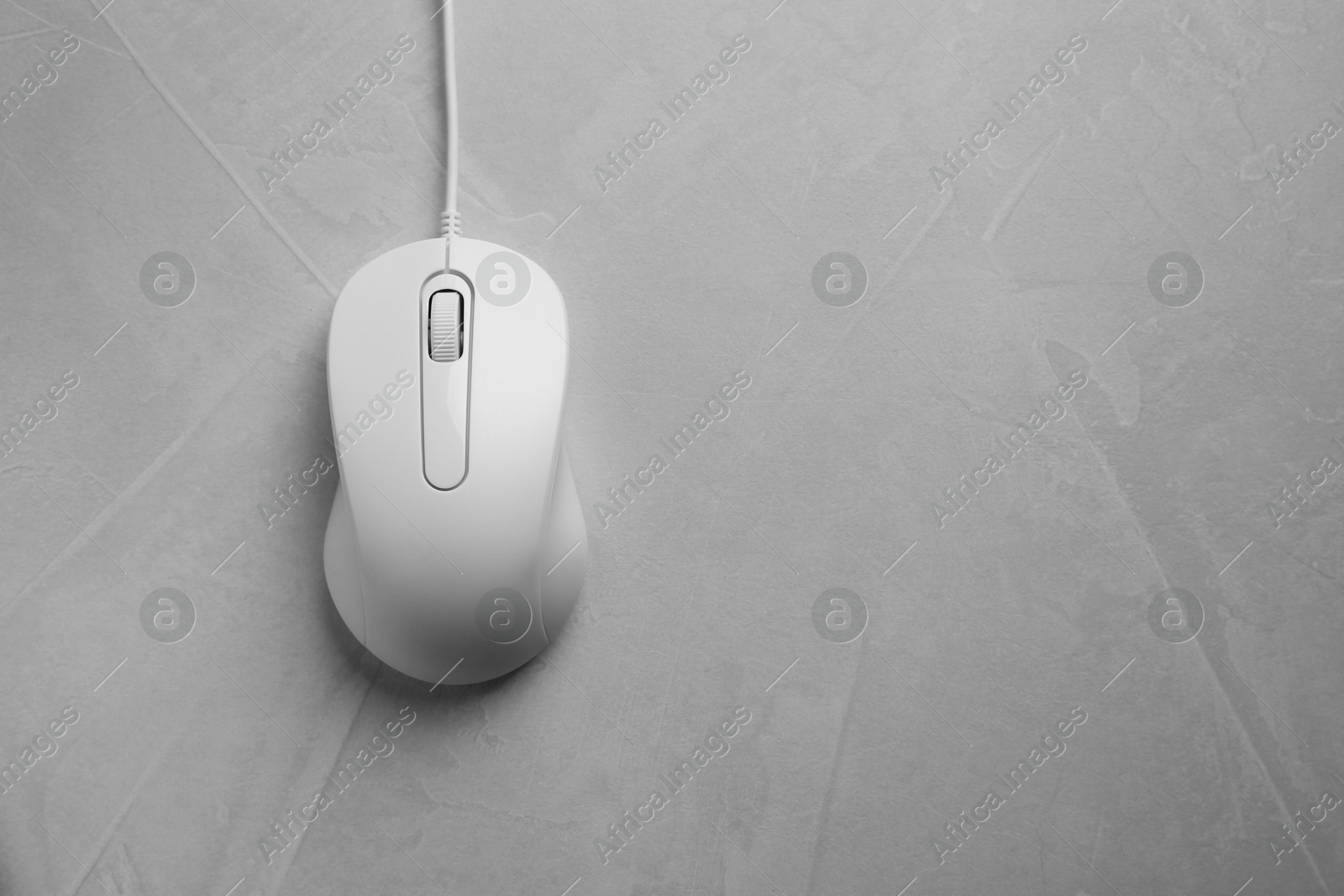 Photo of One wired mouse on grey textured table, top view. Space for text