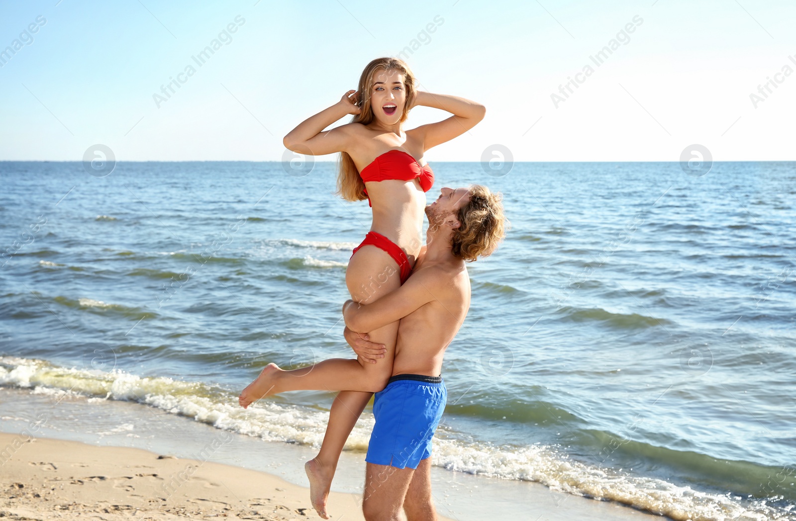 Photo of Happy young couple in beachwear having fun on seashore