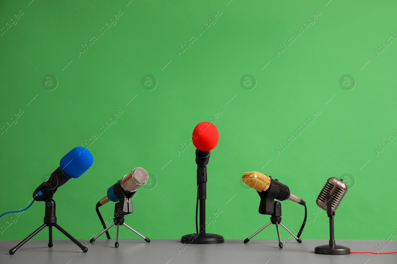 Photo of Microphones on table against green background. Journalist's work