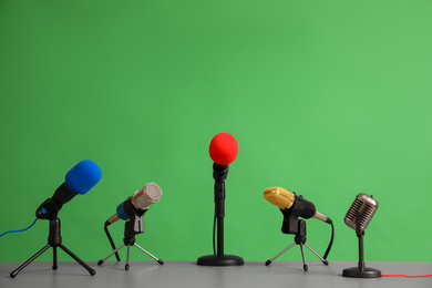 Photo of Microphones on table against green background. Journalist's work