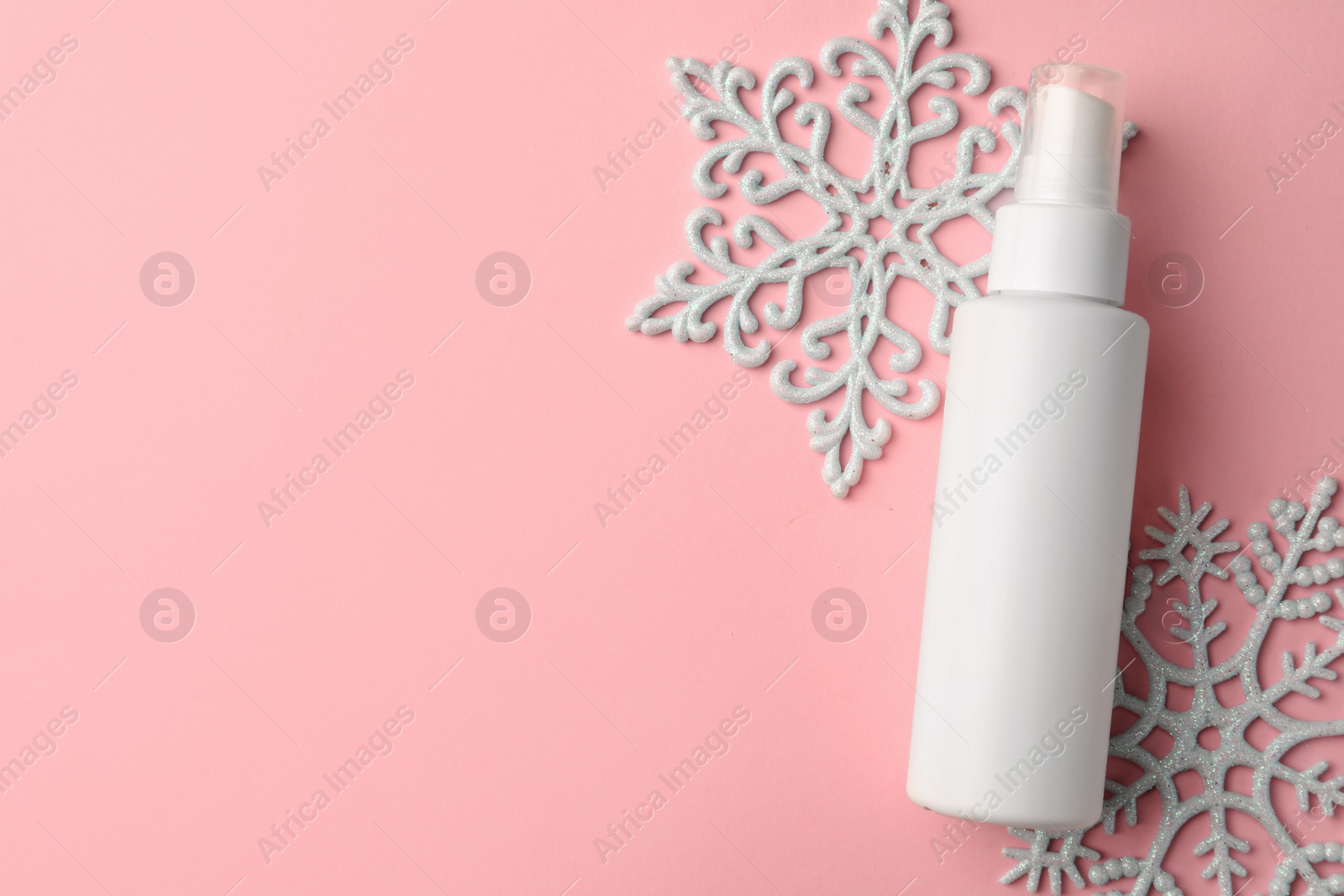 Photo of Winter skin care. Hand cream near snowflakes on pink background, flat lay. Space for text