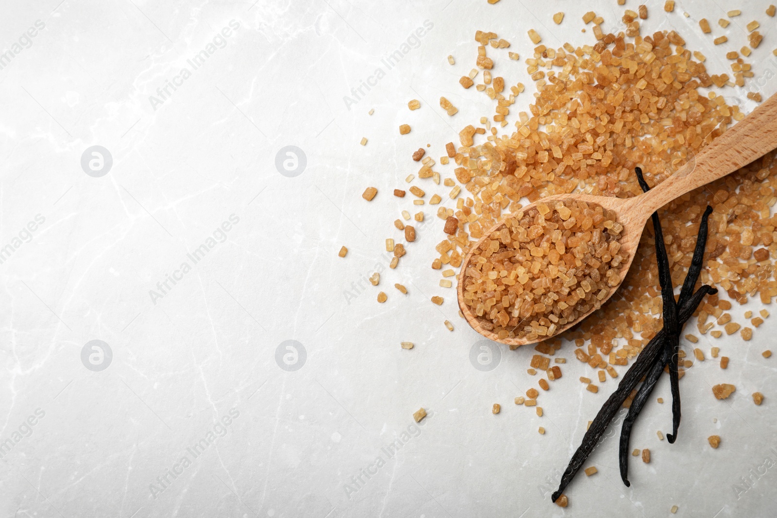 Photo of Spoon with aromatic vanilla sugar and sticks on grey background