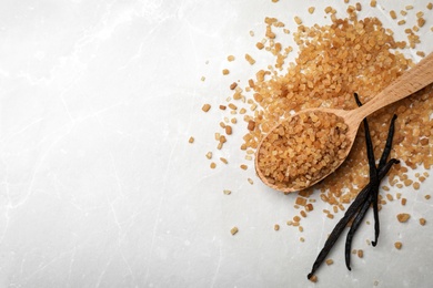 Photo of Spoon with aromatic vanilla sugar and sticks on grey background