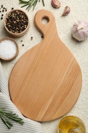 Wooden cutting board, oil and spices on white textured table, flat lay